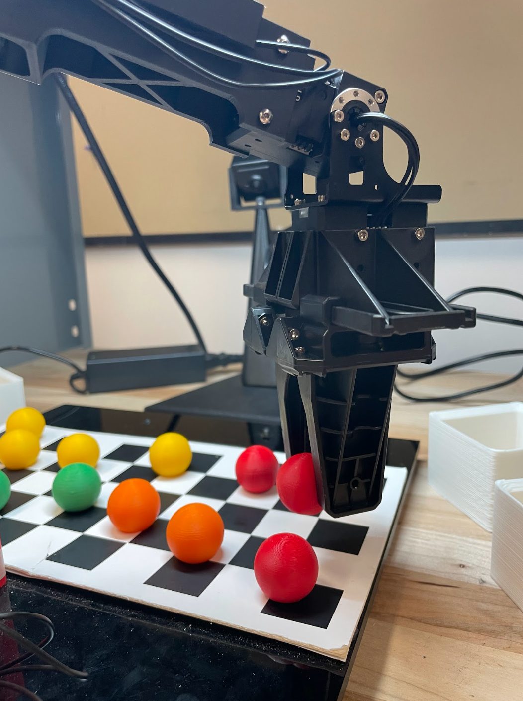OpenMANIPULATOR-X gripper picking a red ball from a checkerboard