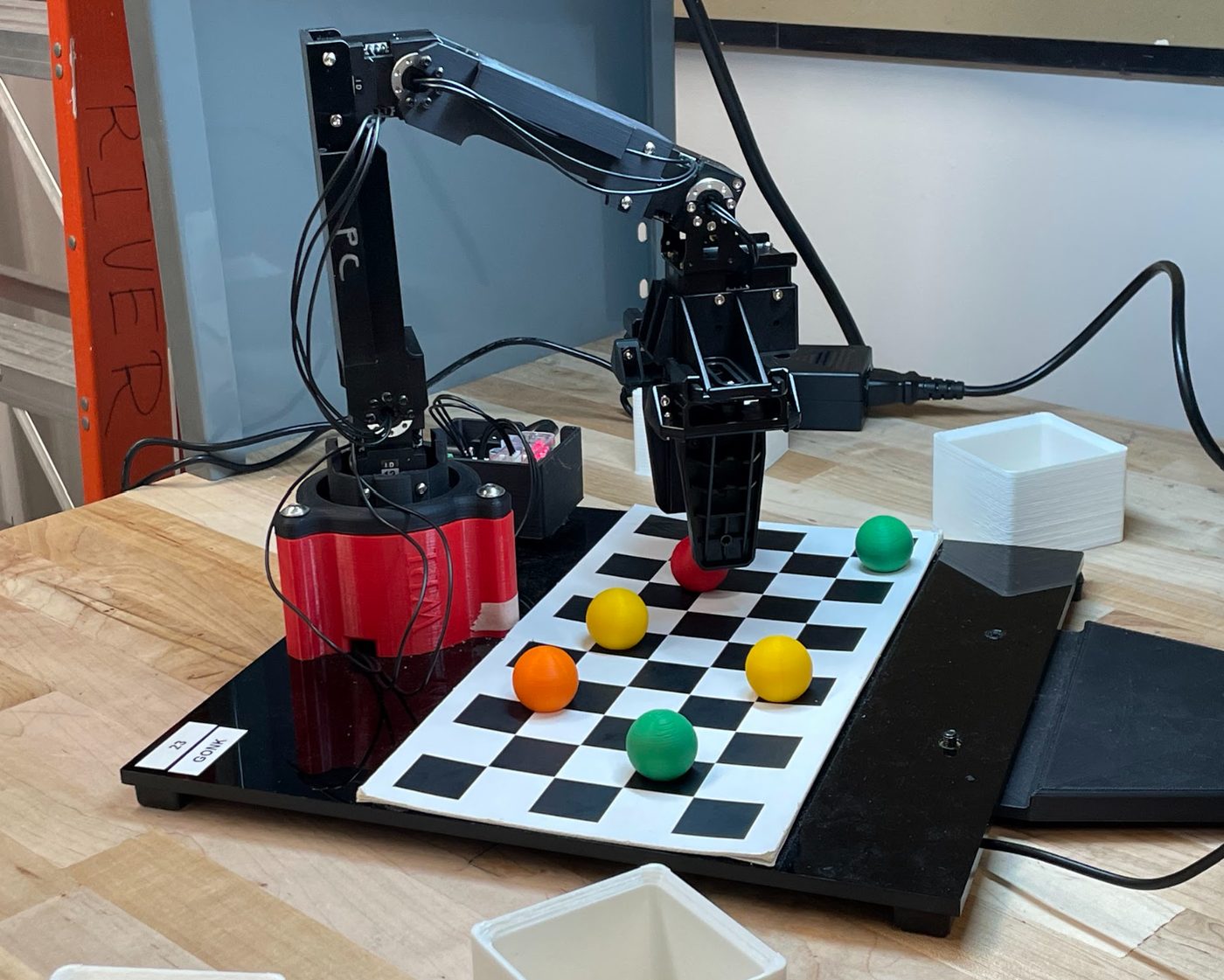 OpenMANIPULATOR-X arm over a checkerboard with coloured balls